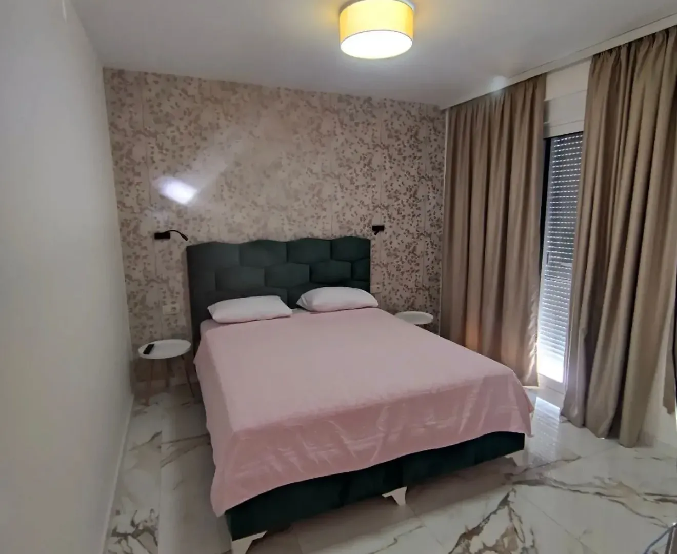 Modern bedroom with a double bed, patterned wallpaper, and access to the terrace.