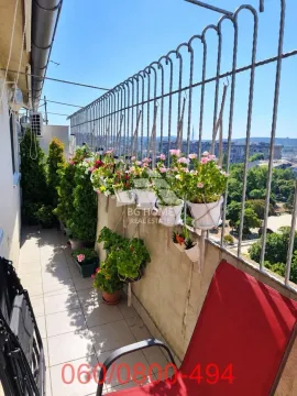 Dugačak balkon sa metalnom ogradom ukrašen saksijama sa cvećem i zelenilom. - image 20