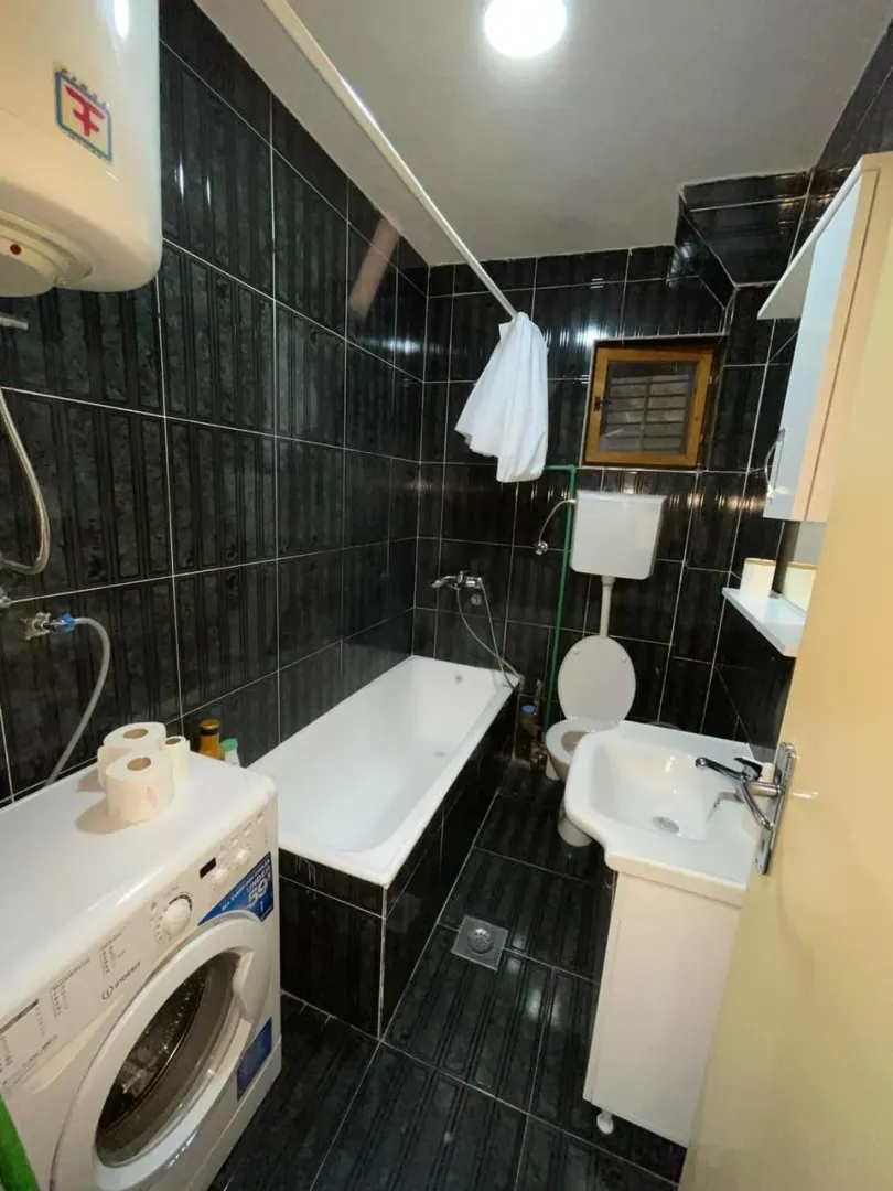 Small bathroom with a bathtub, washbasin, and washing machine.