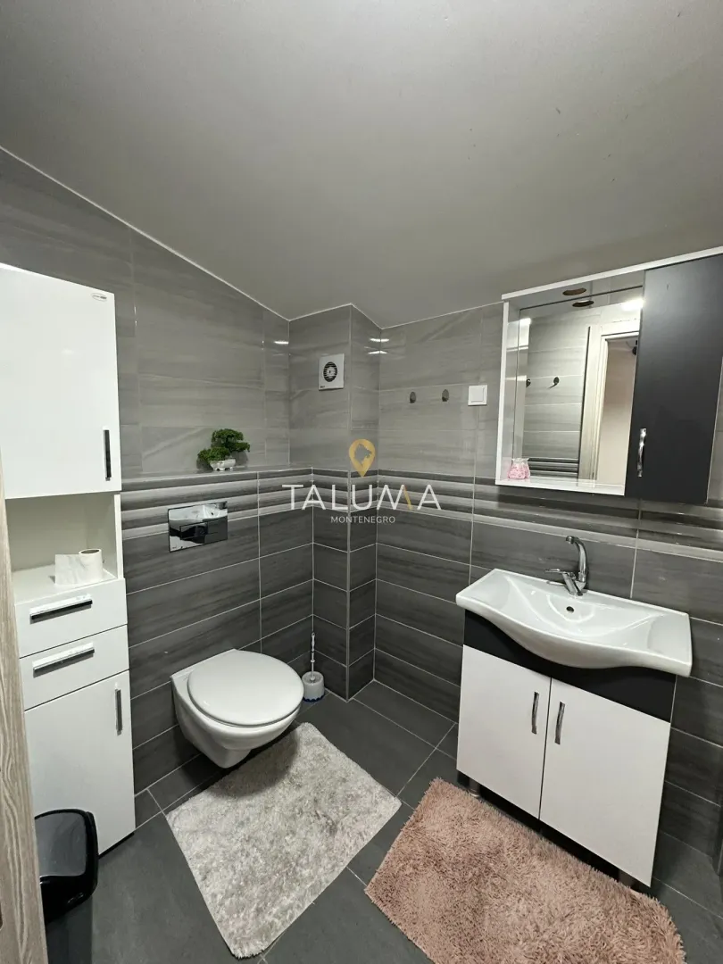 Moderne kupatilo sa tuš kabinom, umivaonikom i ugrađenom sanitarijom.