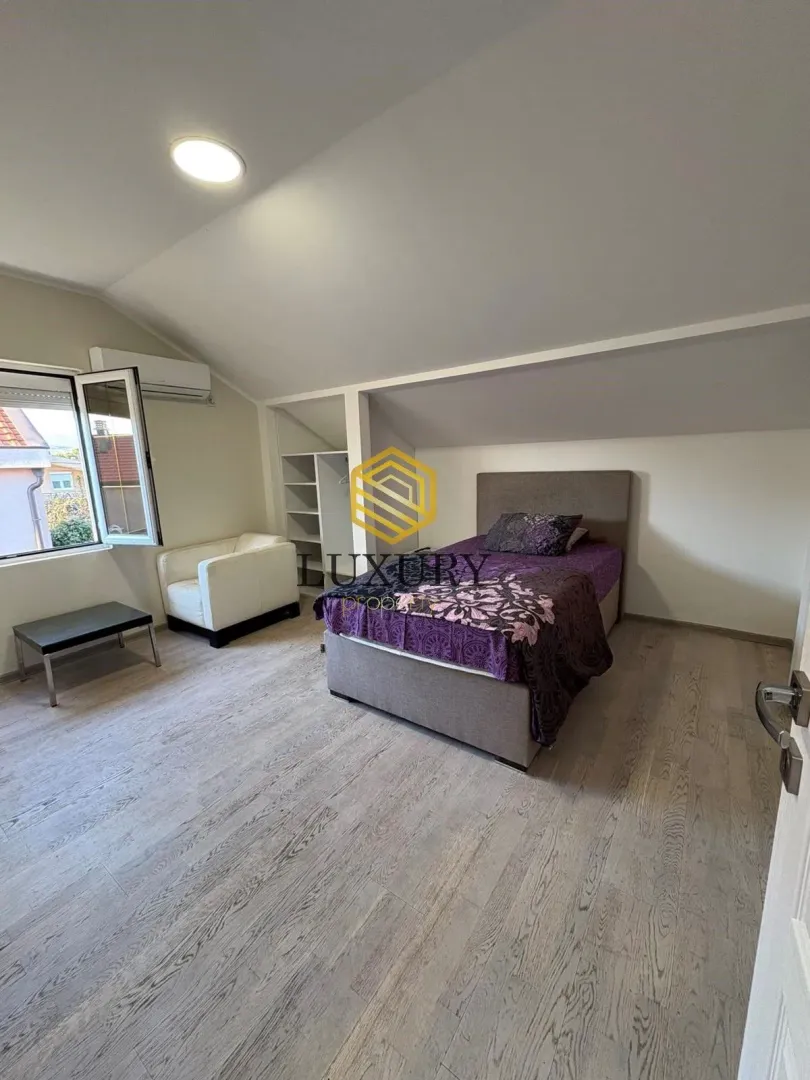Attic bedroom with a bed, armchair, and wardrobe.