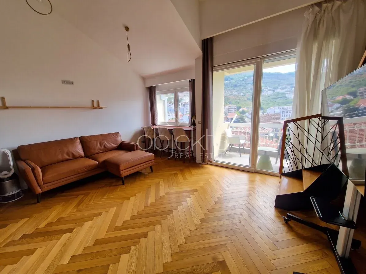 Dnevni boravak sa kožnom garniturom, drvenim parketom i izlazom na terasu.