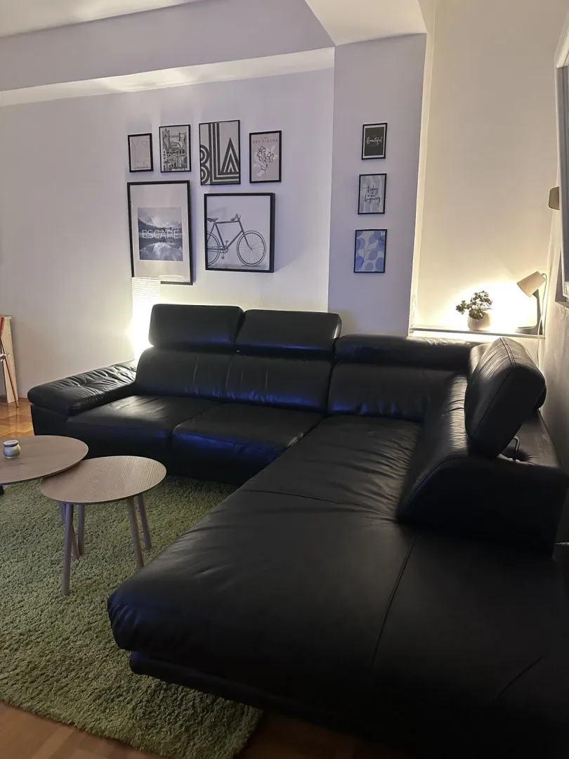 Living room with a black leather corner sofa.