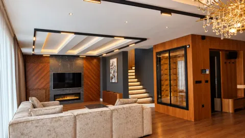 Spacious living room with a sectional sofa, wall-mounted TV, fireplace, and stairs. - image 3