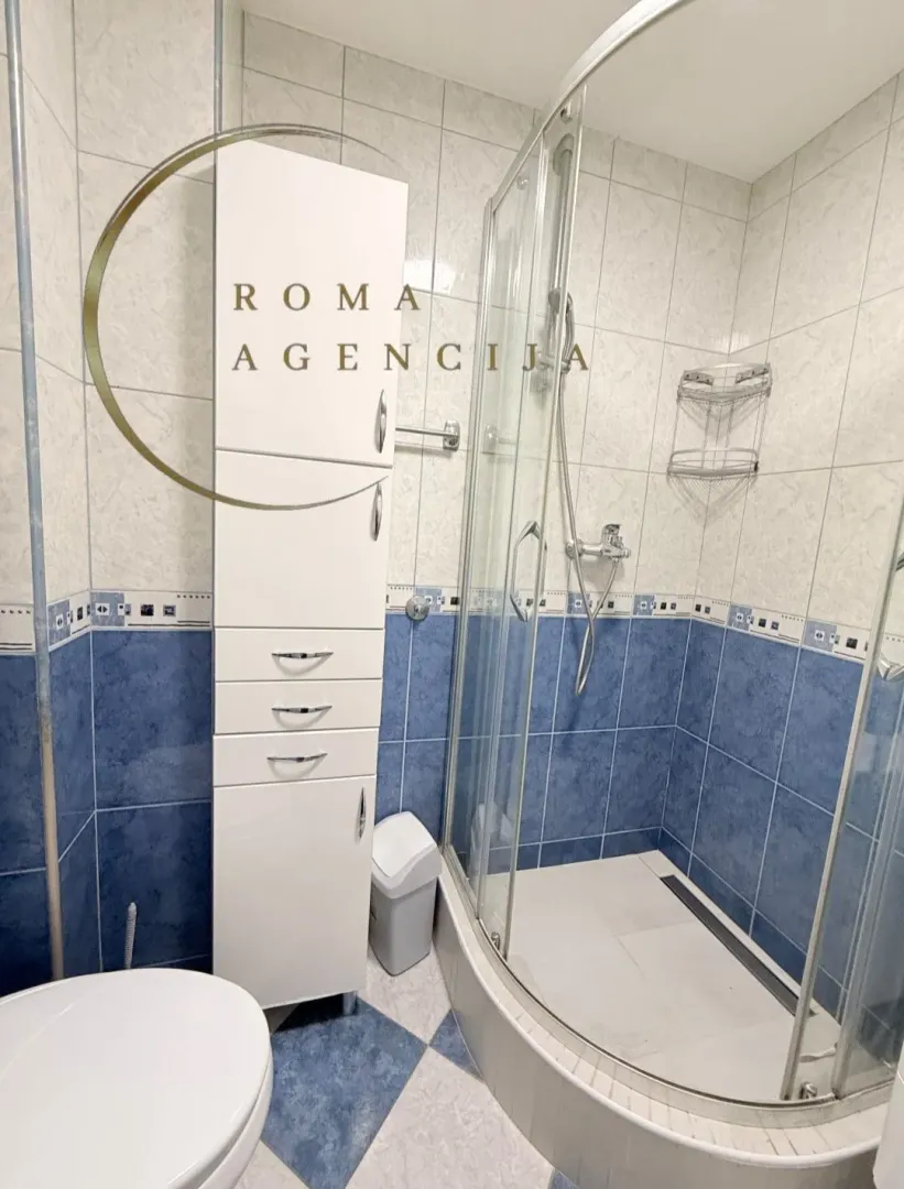 Bathroom with a shower cabin, white cabinet, and blue tiles.