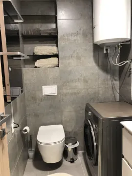 Modern bathroom with grey tiles and a washing machine. - image 21