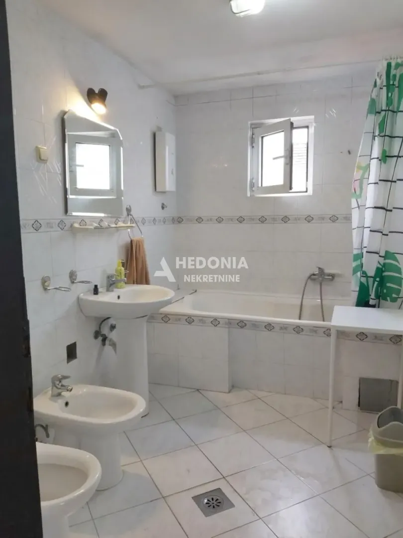 Kupatilo opremljeno sa kadom, umivaonikom i sanitarijama.