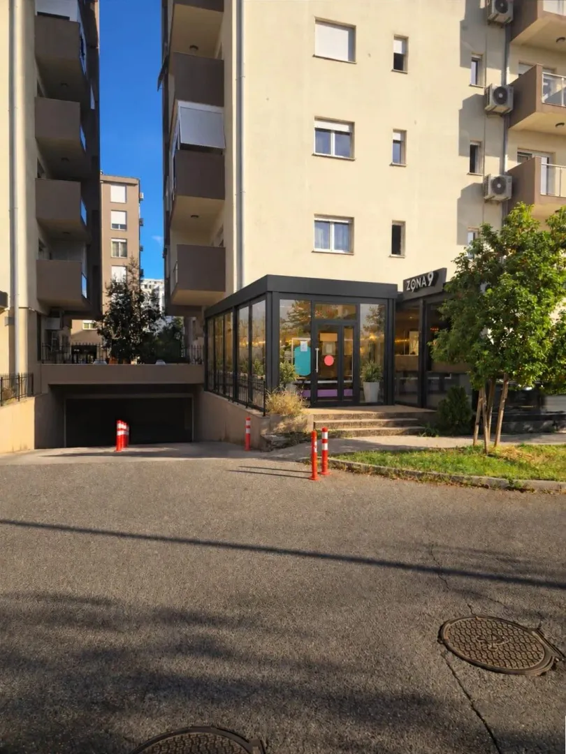 Exterior of a residential building with a ground floor commercial space and garage entrance.