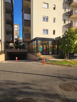 Exterior of a residential building with a ground floor commercial space and garage entrance. - image 7