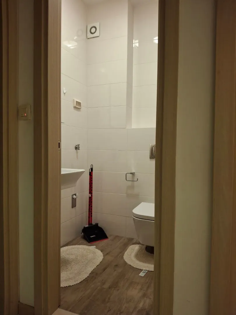 View through the doorway into a tidy bathroom with white tiles.