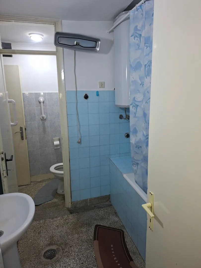 Smaller bathroom with a bathtub, blue tiles, and sanitary fixtures.