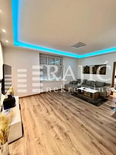 Living room with sofa, TV, and ceiling lighting.