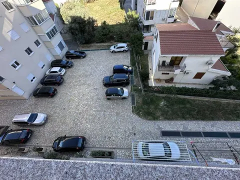 Pogled odozgo na parking prostor sa parkiranim automobilima i okolnim zgradama. - image 15