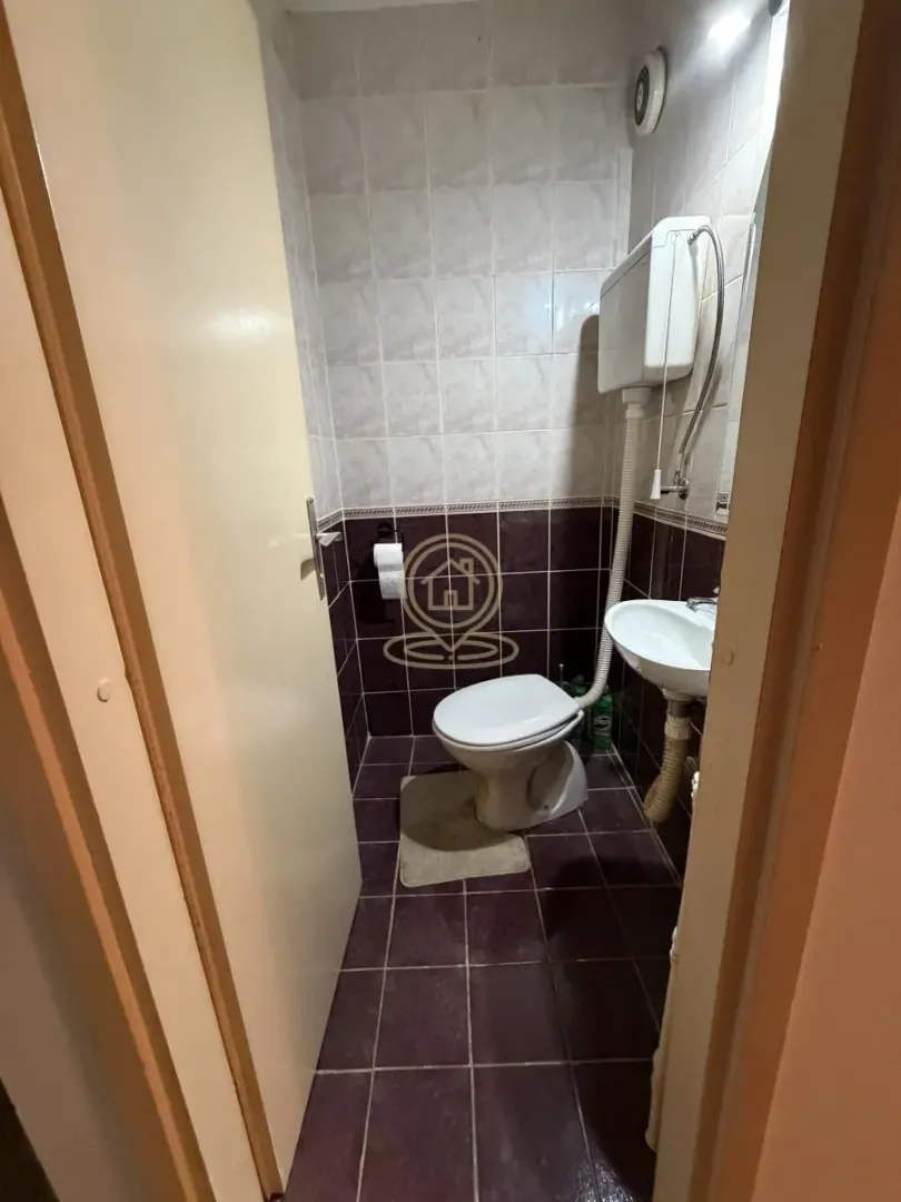 Manje kupatilo sa toaletom i umivaonikom, obloženo pločicama.