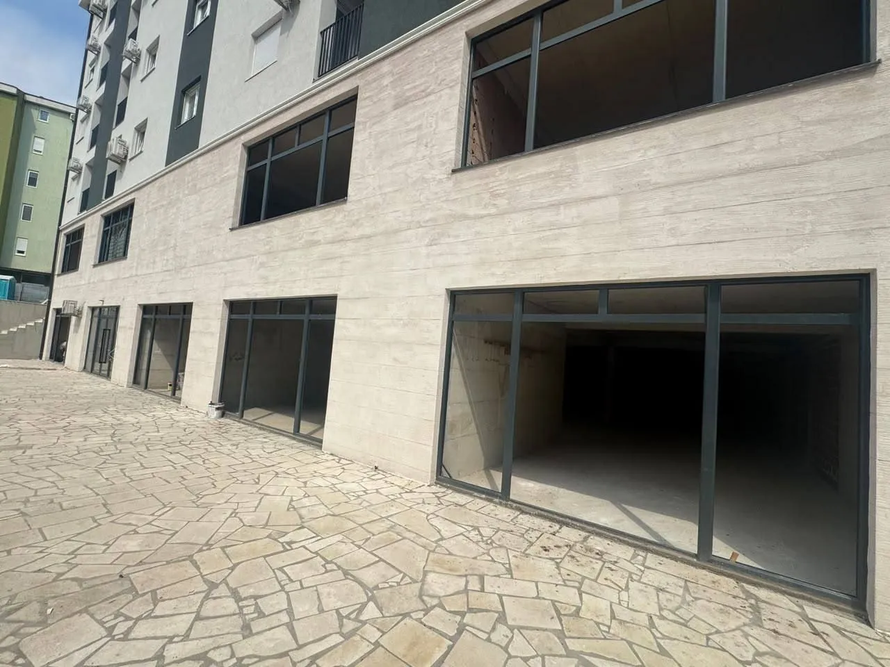 Exterior view of ground-floor commercial space in a residential building with a tiled patio.