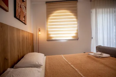 A furnished bedroom with a double bed and a window with blinds. - image 5