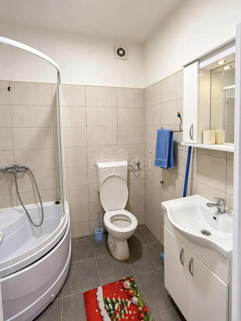 Bathroom equipped with a shower cabin, vanity unit with sink, and toilet.
