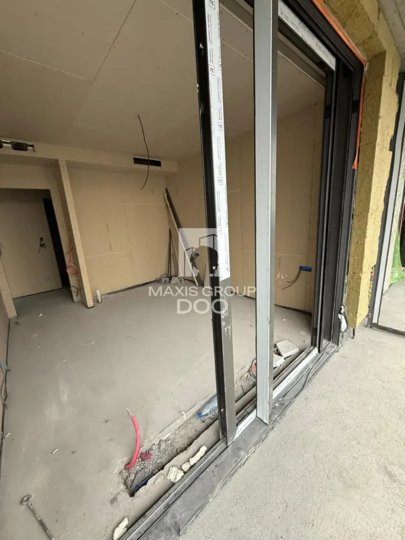 A view of an unfurnished room under construction with installed window frames.