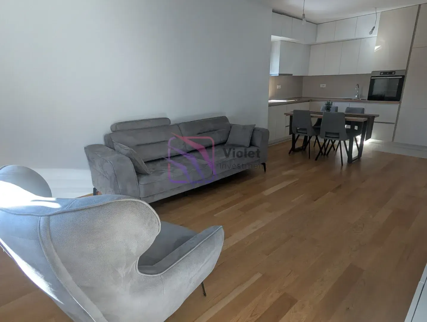 Living room connected to the dining area and kitchen, featuring a sofa and wooden flooring.