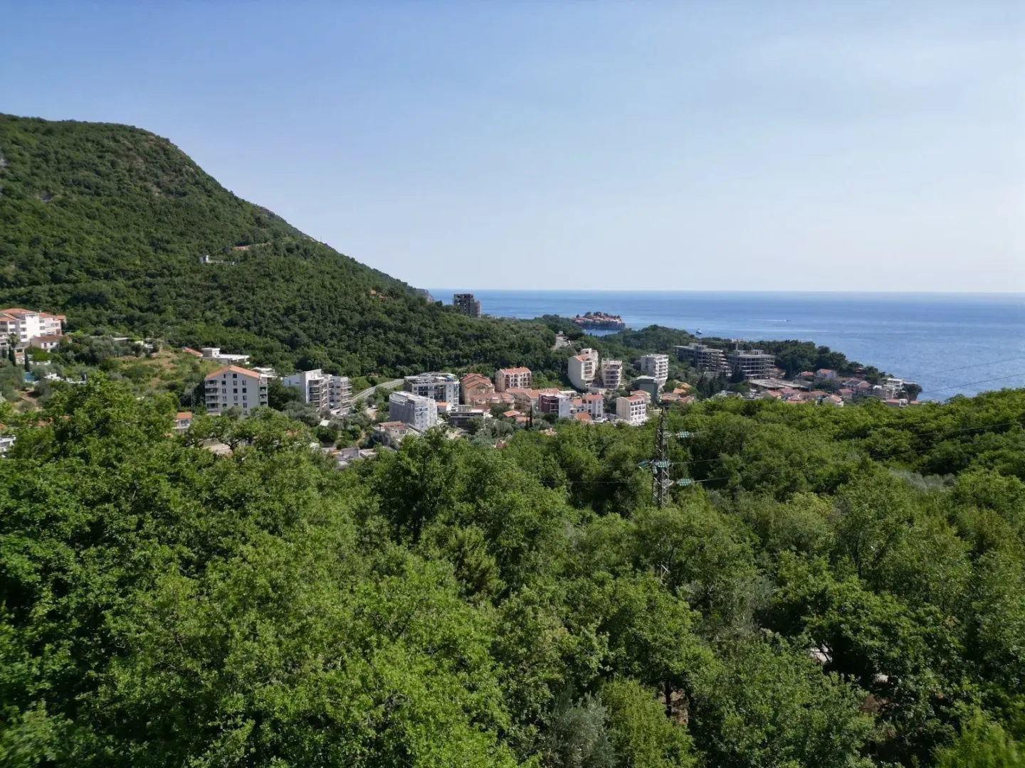 Panoramski pogled na more i naselje okruženo zelenilom.