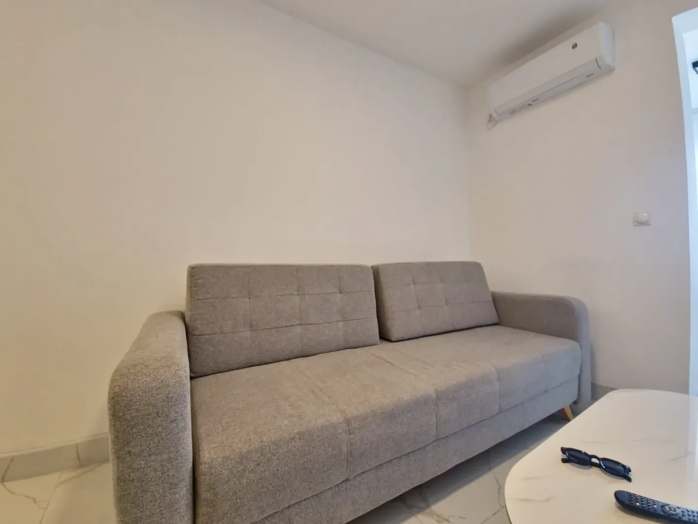 Siva sofa i klima uređaj u dnevnoj sobi.