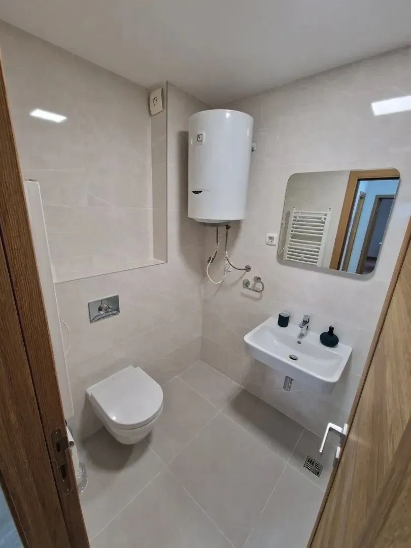 Smaller bathroom with a shower, sink, and water heater.