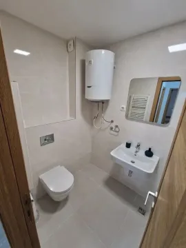 Smaller bathroom with a shower, sink, and water heater. - image 7