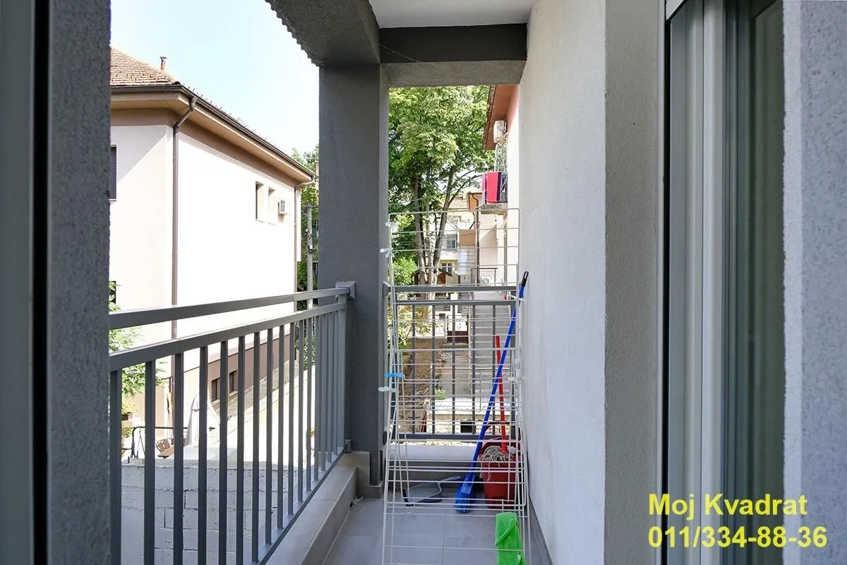 Pogled sa balkona na okolne zgrade i zelenilo.