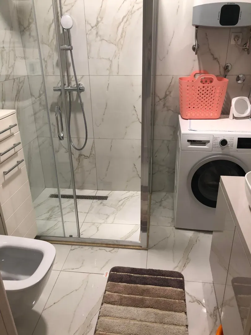 Kupatilo sa tuš kabinom, veš mašinom i sanitarijama.