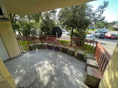 Covered terrace with metal railing and views of the street and greenery. - image 8