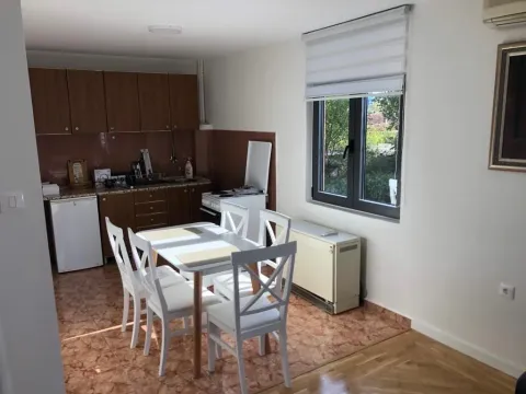 Dining area with a kitchen equipped with wooden cabinets and a white table with chairs. - image 3