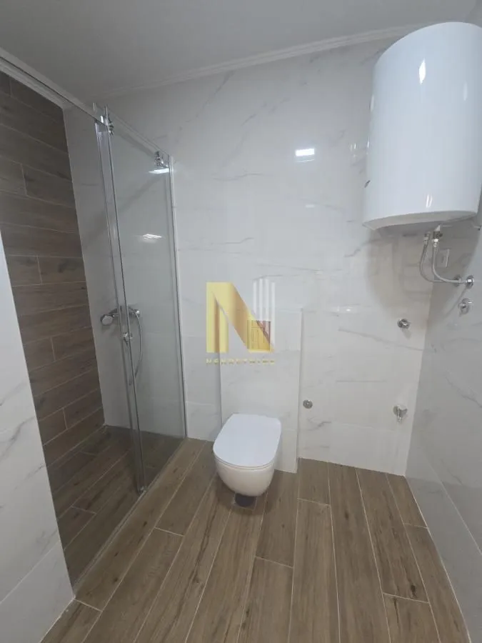 Moderno kupatilo sa tuš kabinom, WC šoljom i bojlerom.