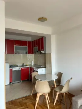 Kuhinja sa crvenim elementima i trpezarijskim stolom sa četiri stolice. - image 7