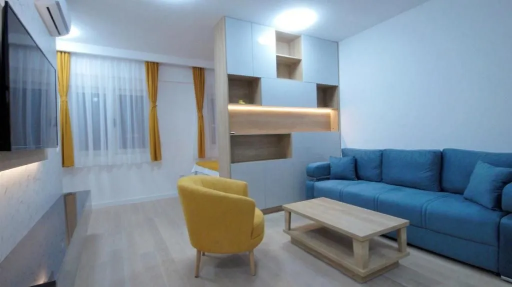 Living room with a blue sofa, yellow armchair and wall-mounted TV.