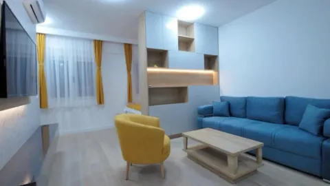 Living room with a blue sofa, yellow armchair and wall-mounted TV. - image 2