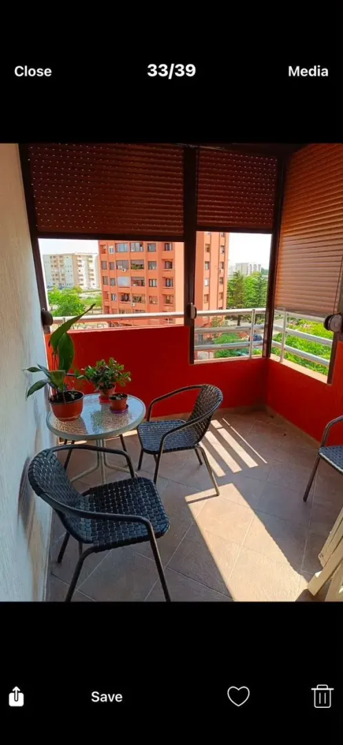 Natkriveni balkon sa garniturom za sedenje i pogledom na gradsko okruženje.