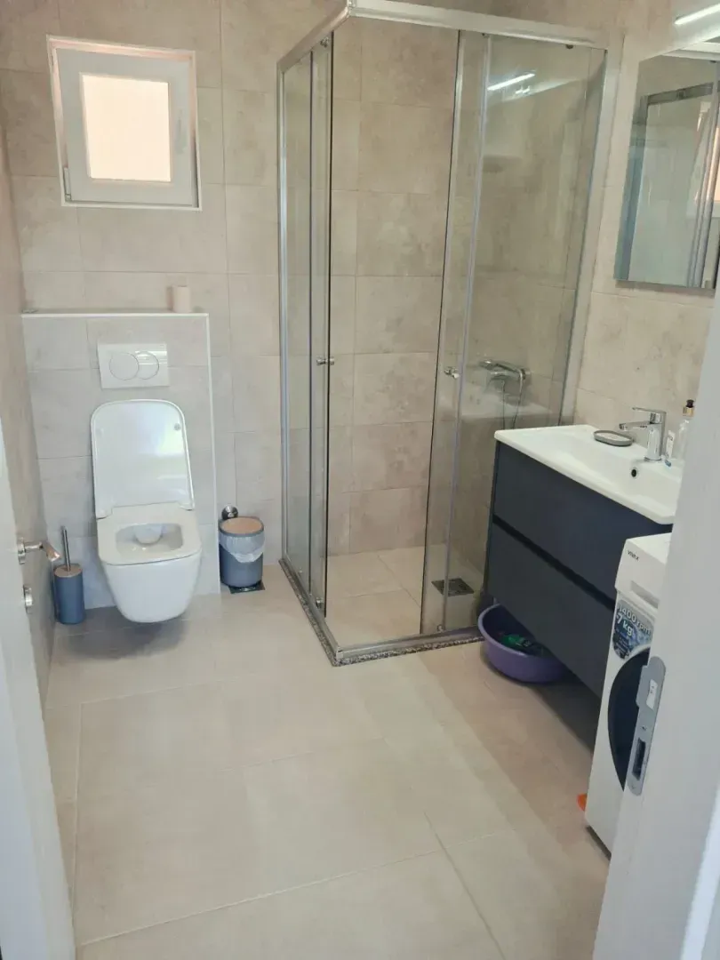Modernly equipped bathroom with a shower cabin, vanity and toilet.