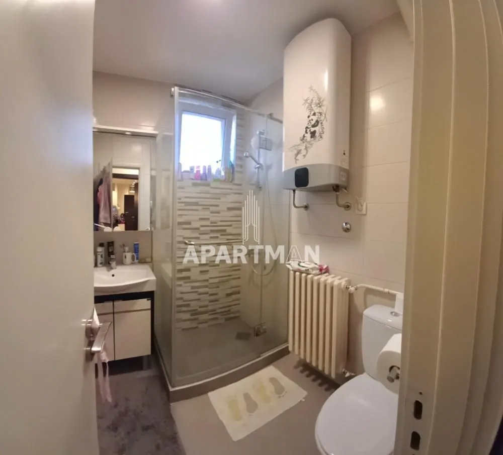 Kompaktno kupatilo sa tuš kabinom, umivaonikom, WC šoljom i bojlerom.