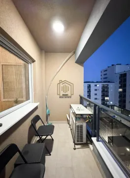 Manji natkriveni balkon sa stolicama i pogledom na zgrade u večernjim časovima. - image 2