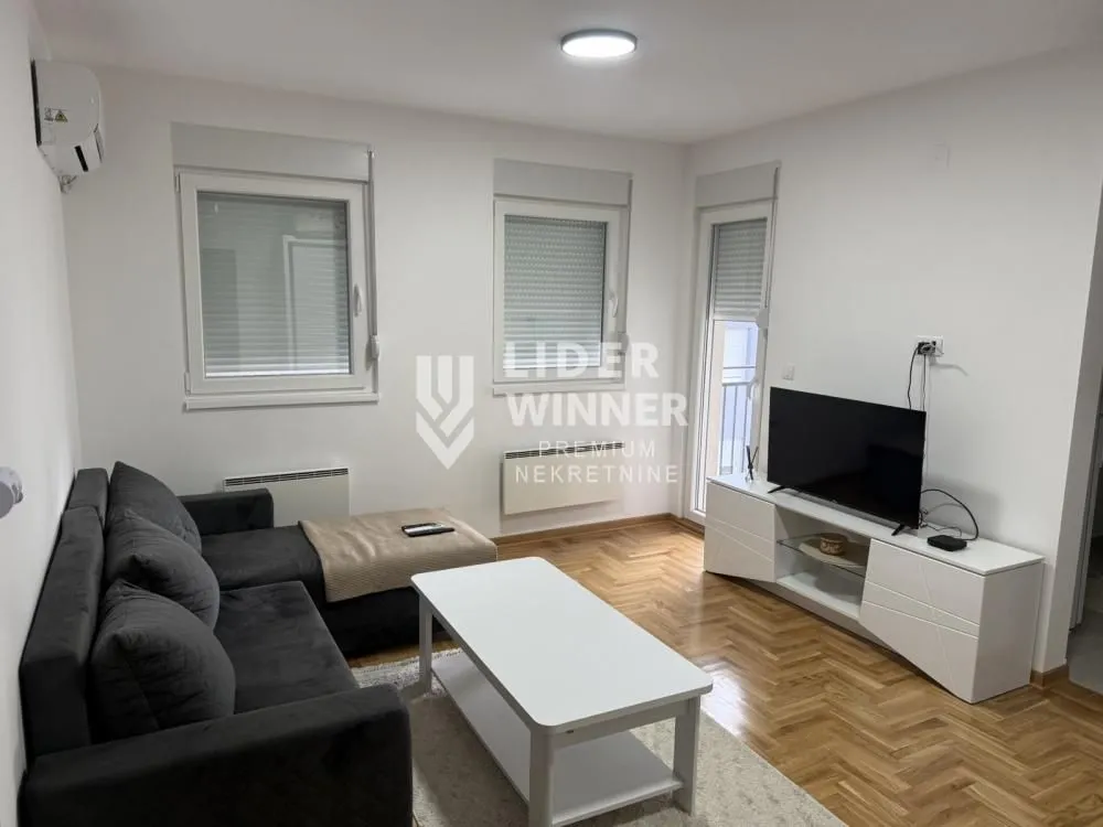 Dnevna soba sa garniturom, stočićem i televizorom.