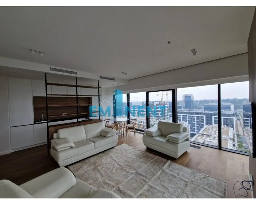 Spacious living room with seating area and large glass surfaces overlooking the city.
