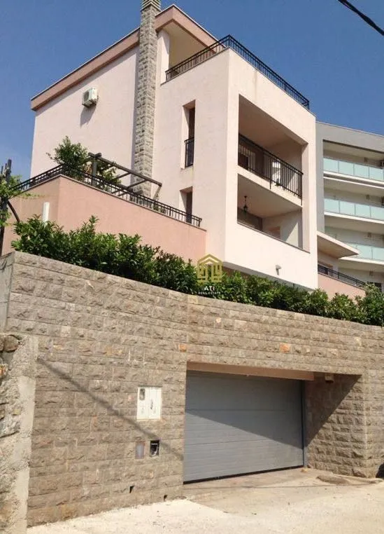 Exterior of a modern multi-family house with a stone wall and garage.