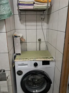 Bathroom with a washing machine and a towel shelf. - image 6