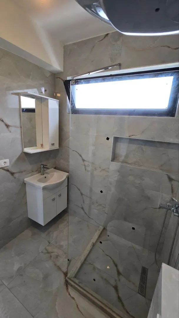 Savremeno opremljeno kupatilo sa tuš kabinom i umivaonikom.