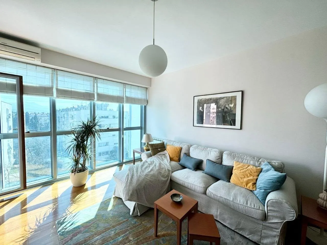 Bright living room with a sofa and large windows.