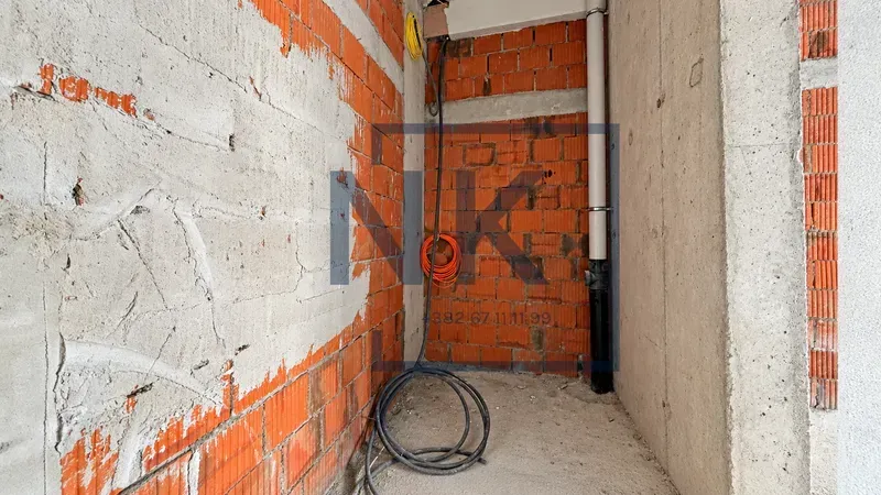 Unfinished interior with exposed bricks and installations under construction.