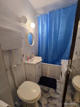 Manje kupatilo sa umivaonikom, WC šoljom, kadom i plavom zavesom za tuširanje. - image 8