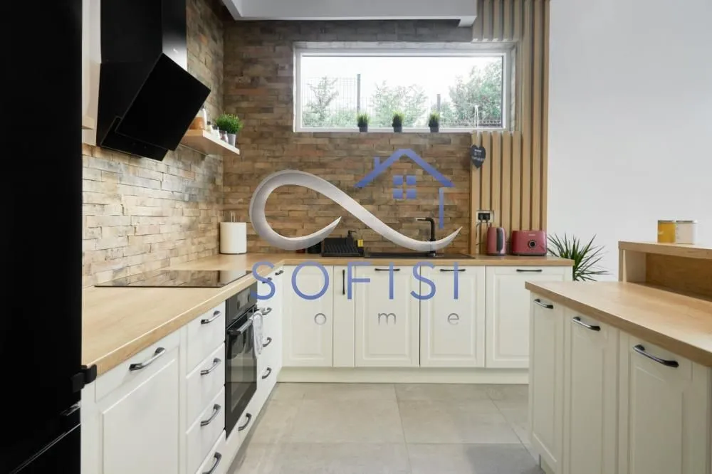 Modern kitchen with white cabinets, wooden countertops, and a decorative stone wall.