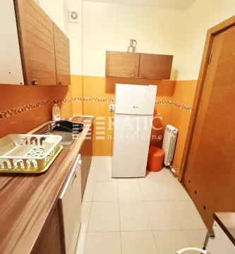Smaller kitchen with a sink, refrigerator, and wooden cabinetry. - image 7
