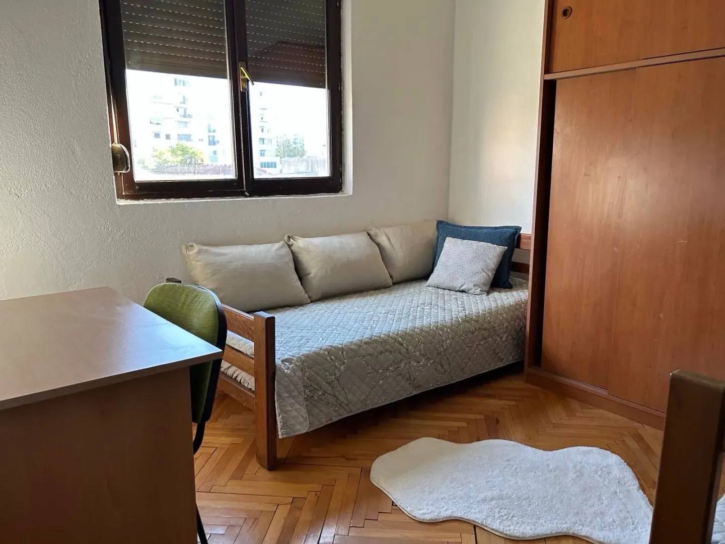 Small bedroom with a bed, wooden wardrobe, and a desk.